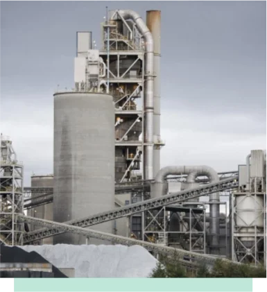 Cement plant with tall preheater tower and conveyor systems.