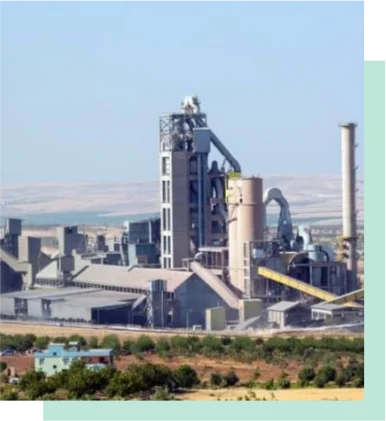 Cement plant with tall tower and silos in desert landscape.